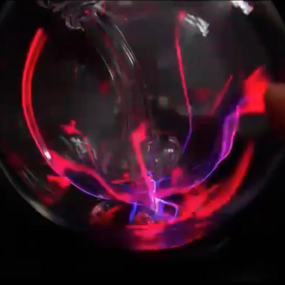 Close-up of a glowing glass object with red and purple lights on a black background